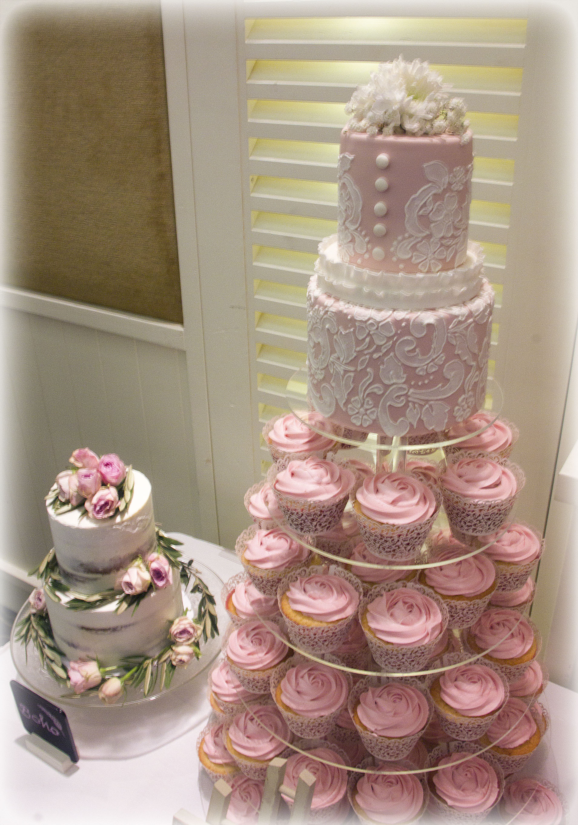 Pink Lace two tier wedding cake with pink swirl cupcakes on a 5 tier cake/cupcake acrylic stand.